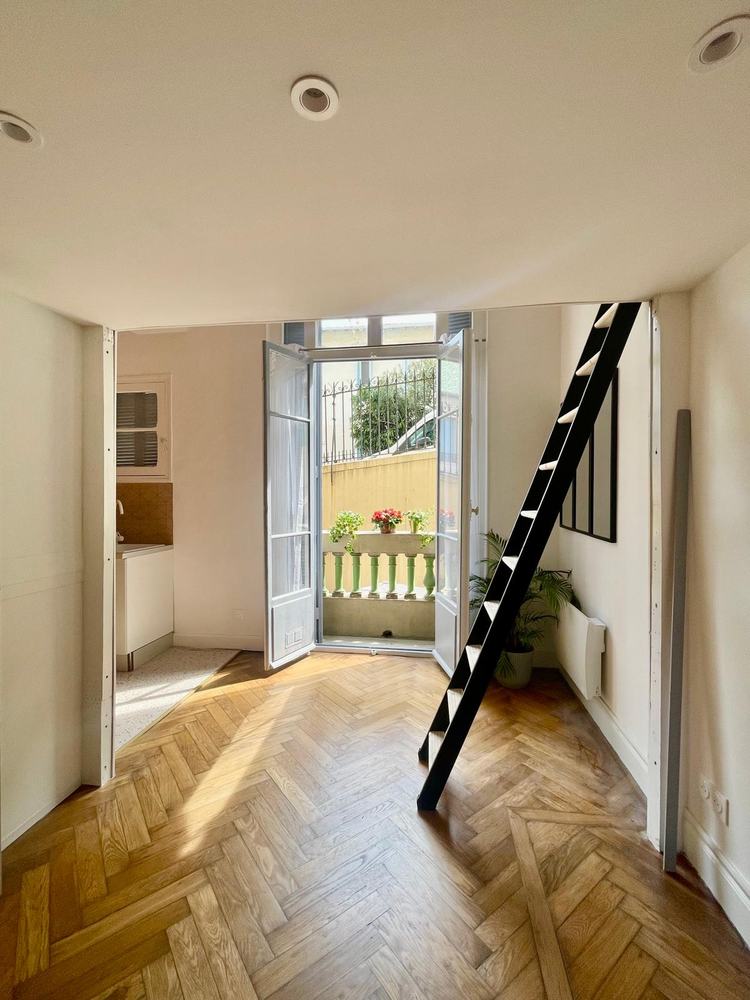 Studio Magnan après travaux avec parquet, grande fenêtre et échelle vers la mezzanine
