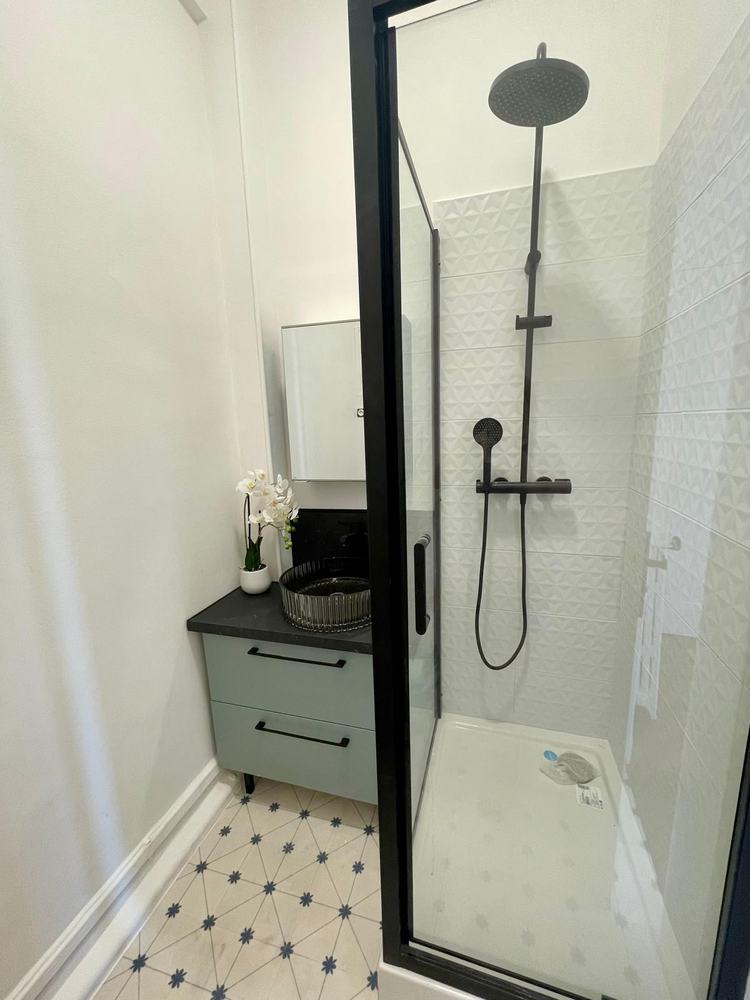 Salle d’eau réalisée avec douche noire et meuble vert